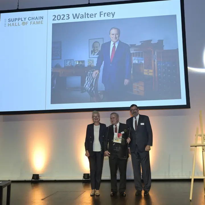 Walter Frey mit Laudator Gerhard Schürmann auf der Bühne, im Hintergrund sein Porträt